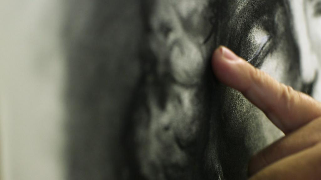 Close up of Jimmy O'Neal's hand as he blends the charcoal on his cast drawing.