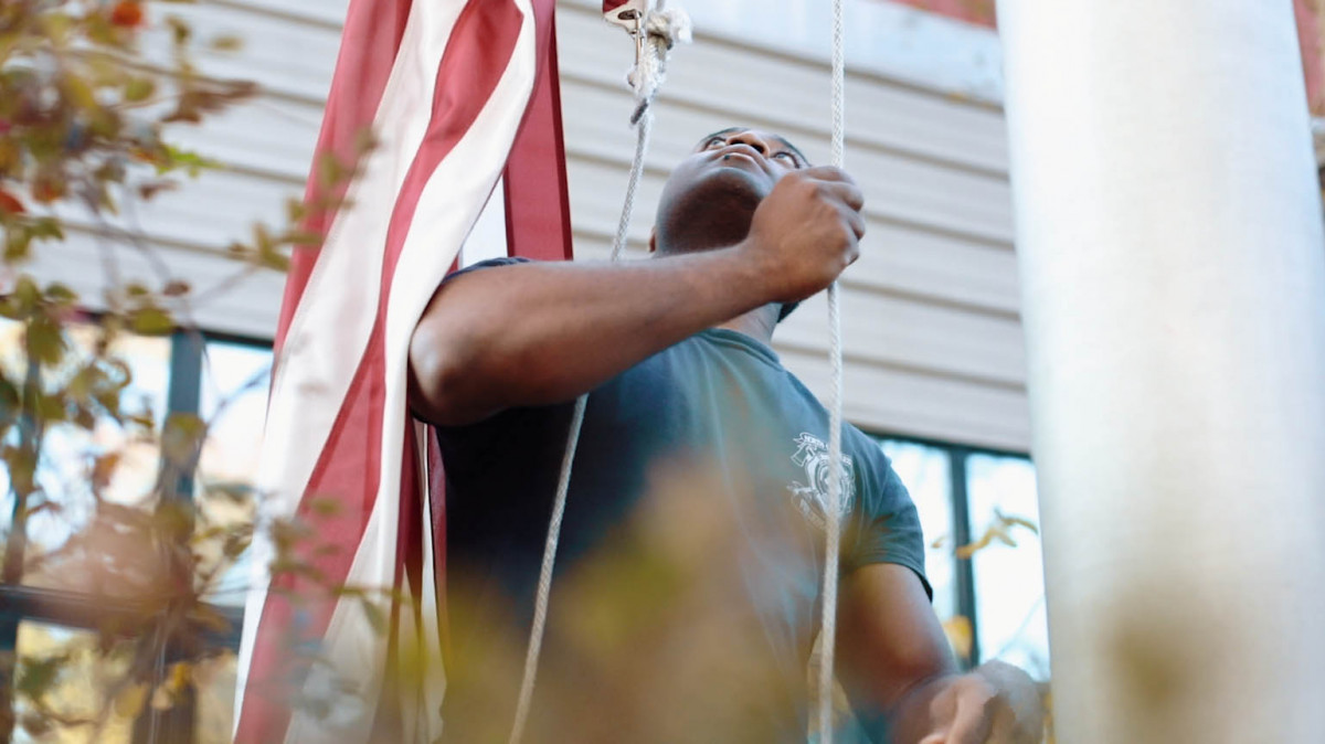 Man raising American flag on pole