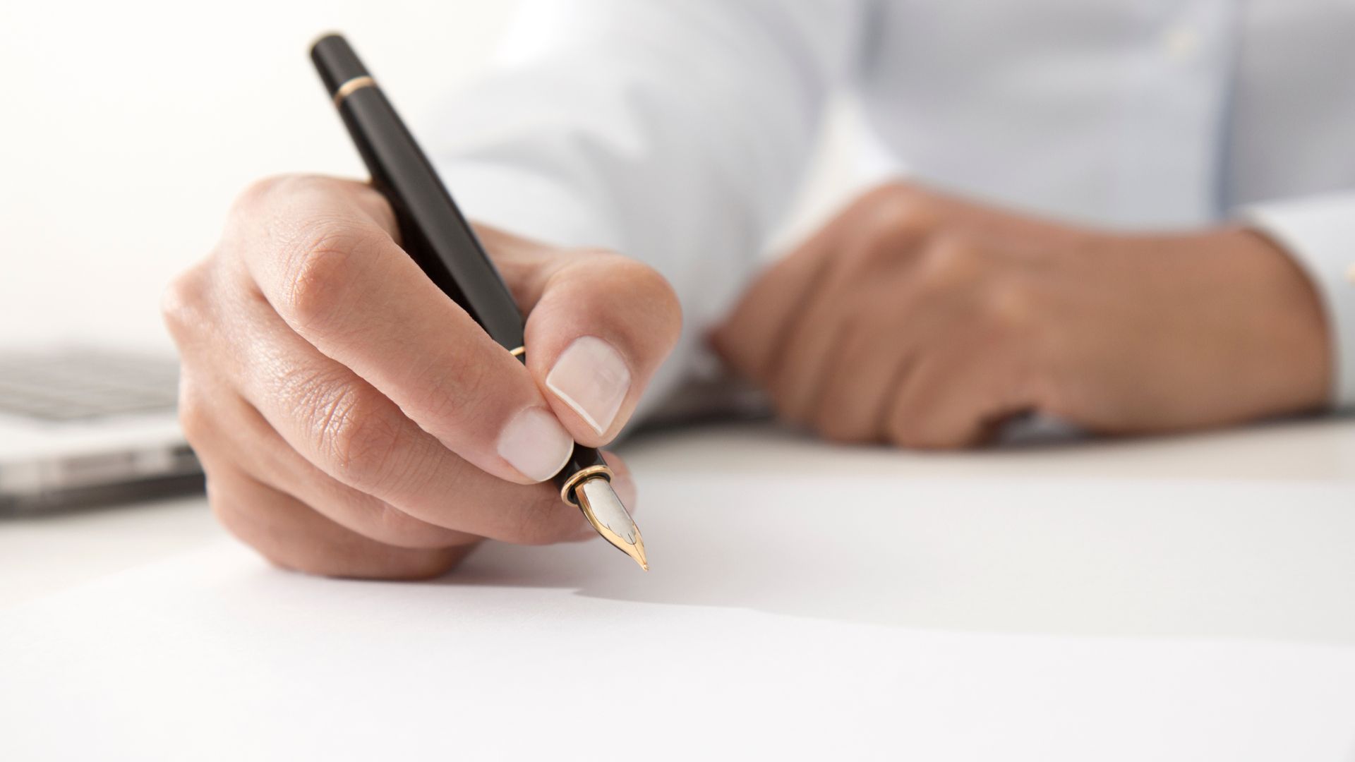 A hand holding a pen, getting ready to sign document