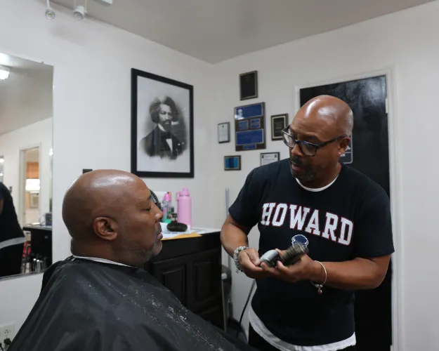 Michael Miller (R), the owner of Michael & Co Barber Shop, talks about the impending presidential election while he cuts client Terry Base's hair (L) in West Ashley. July 25, 2024.