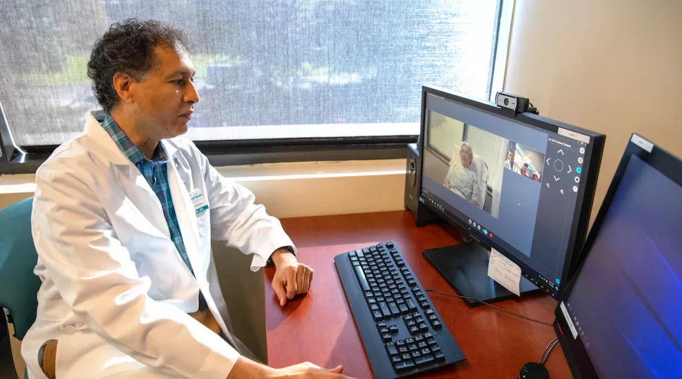 Doctor at a desk with patient via Telehealth