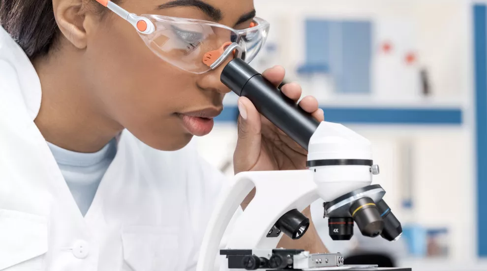 African American young woman looking through a microscope