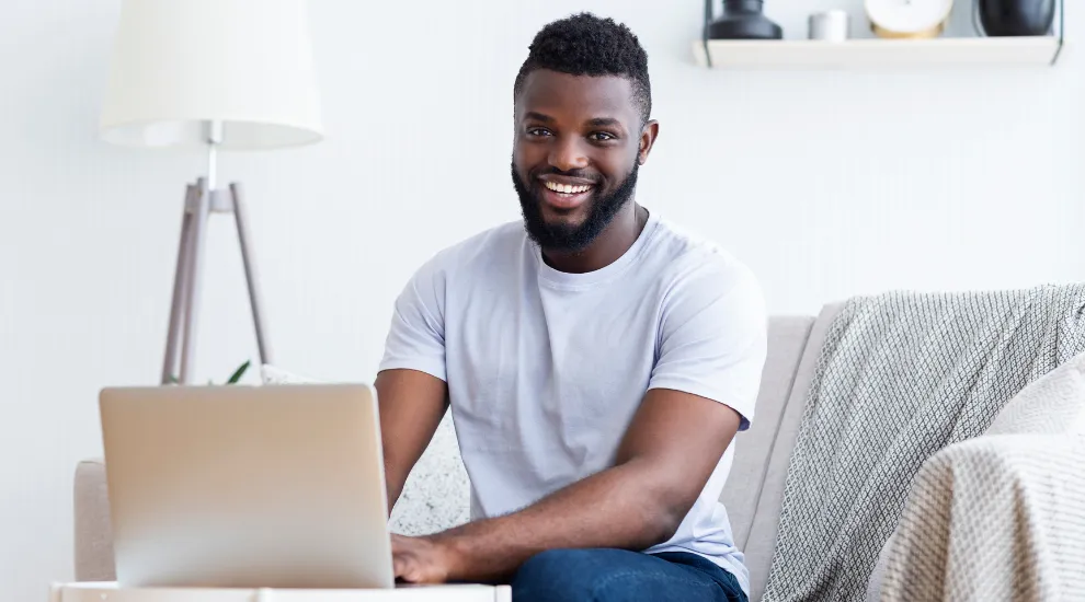 photo of African-American man sitting on a sofa using a laptop
