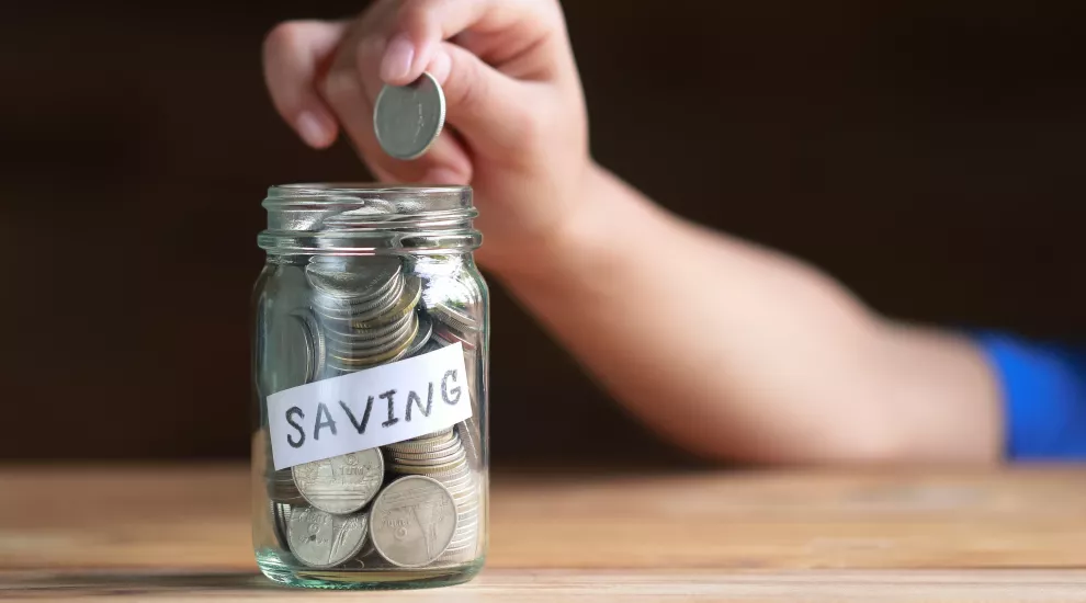 Dropping a coin into a jar labeled savings