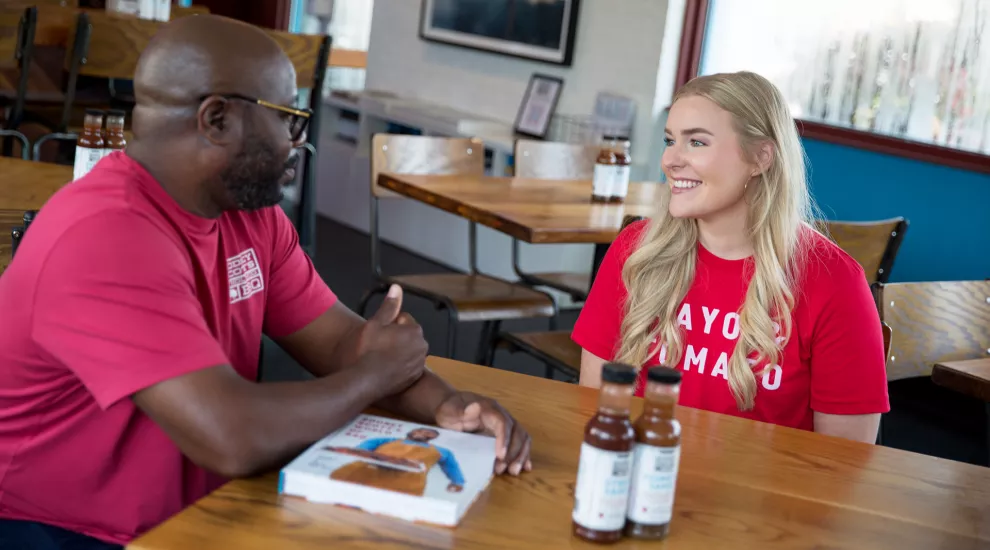 Devyn and Rodney Scott sit at a table inside of a barbecue restaurant.