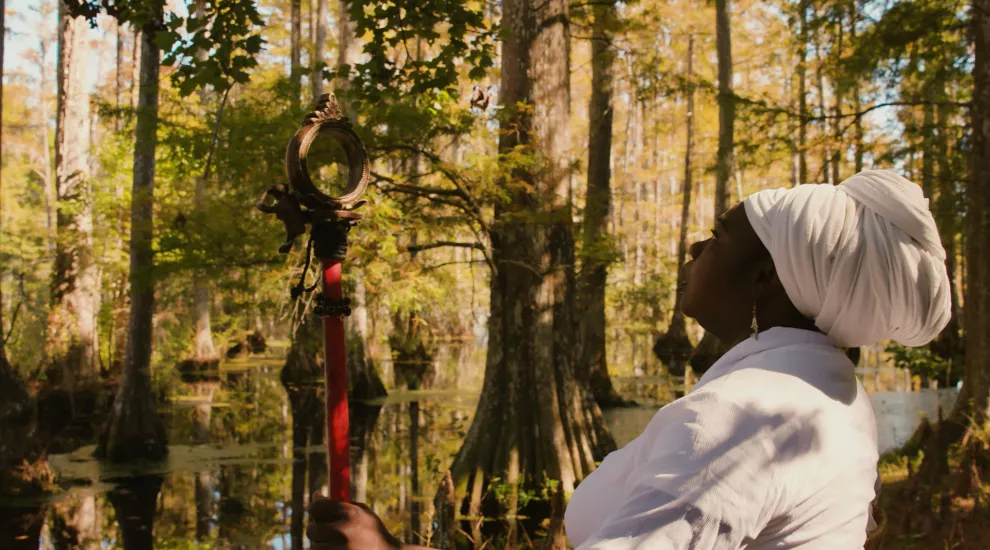 photograph of an African American woman wearing traditional Gullah Folk wardrobe standing near a body of water in the lowcountry of south carolina.