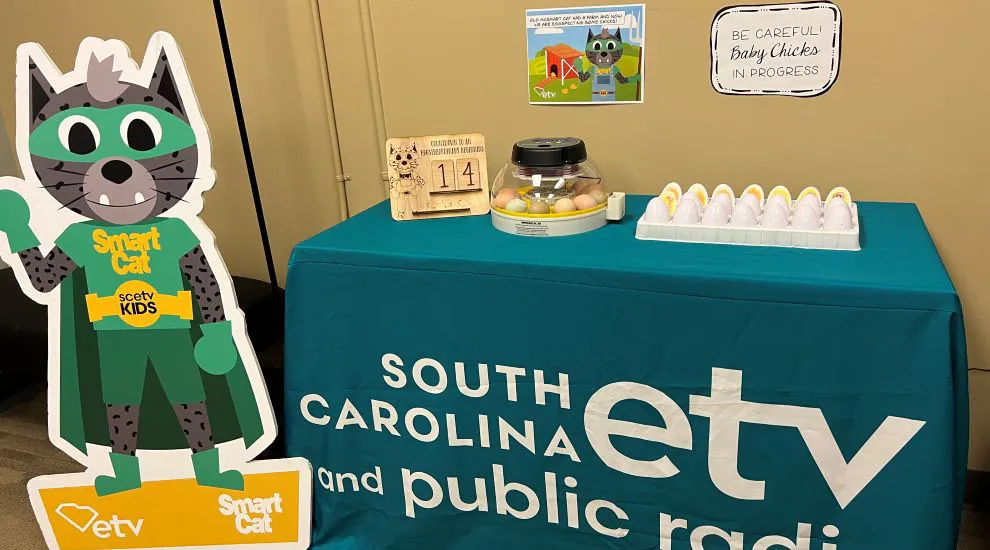 photo of chicken eggs in incubator on table with ETV tablecloth and Smart Cat 'standee' nearby