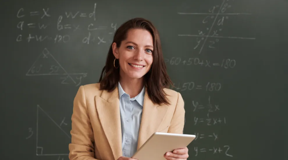 photo of teacher standing in front of chalkboard with math equations on it