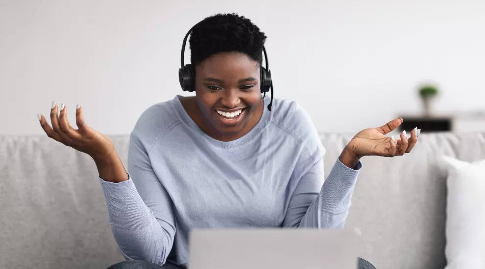 photo of a woman looking at laptop screen and wearing headphones