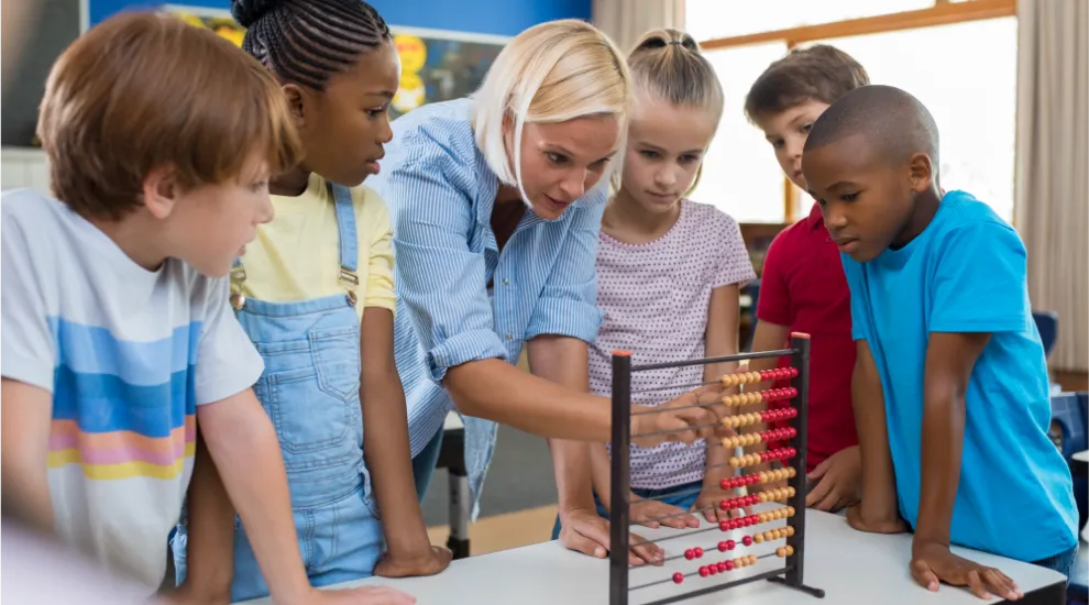 photo showing several elementary school students using an abacus with a teacher