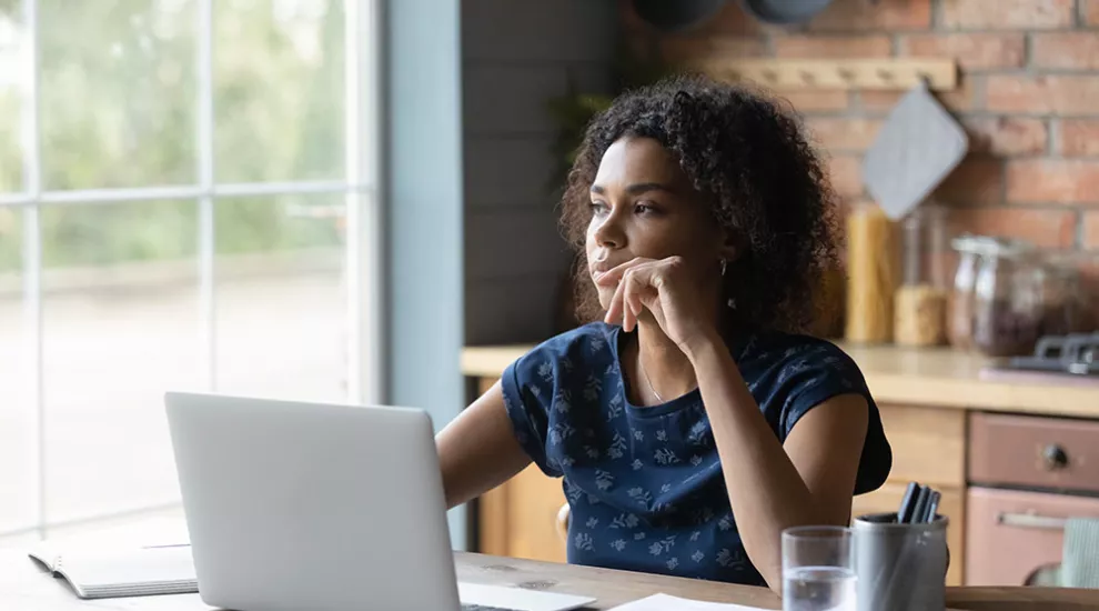 Young woman on laptop contemplating