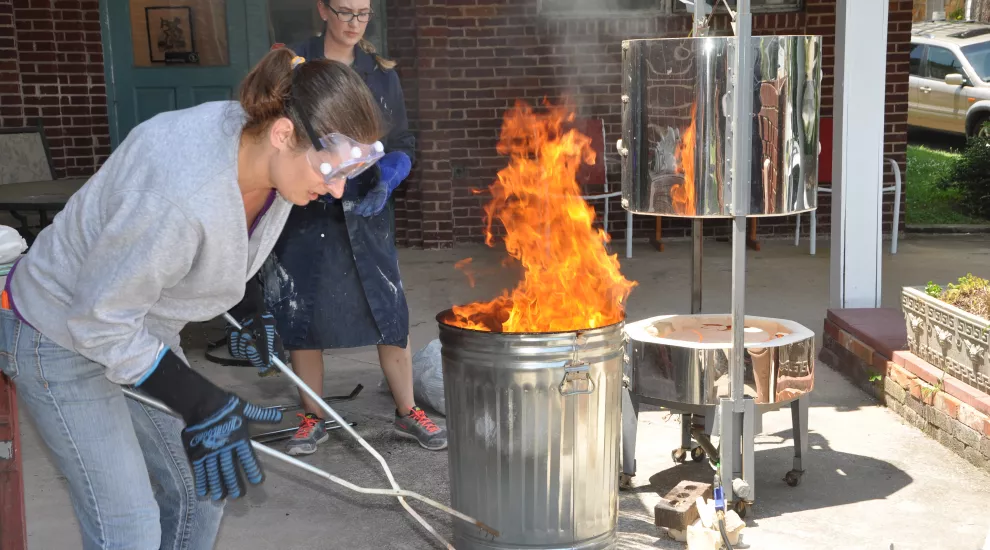 Female artist with flaming trashcan 