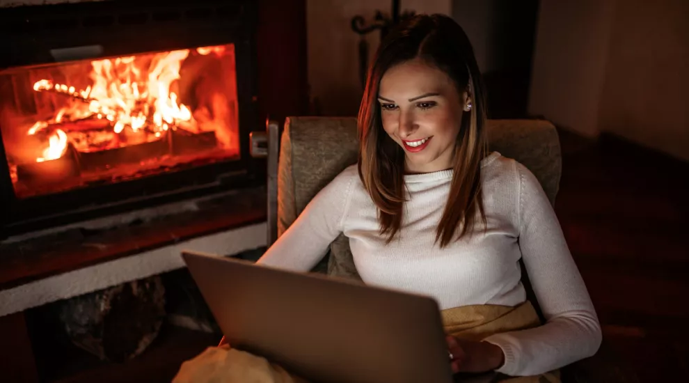 image of woman sitting by a fireplace looking at a laptop