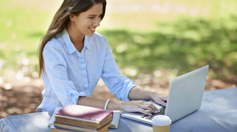 Woman sitting outside on laptop smiling
