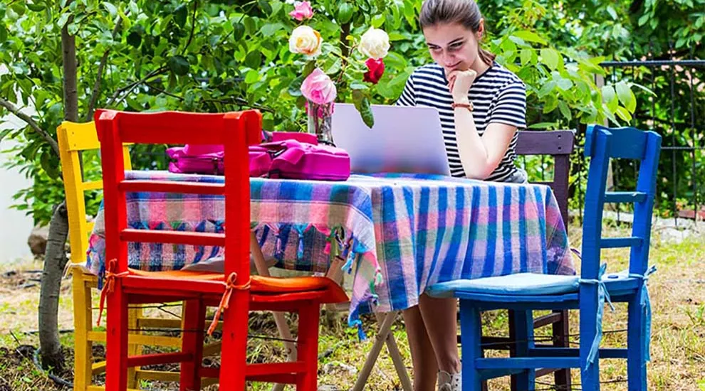 Teacher sitting at table outside working on laptop