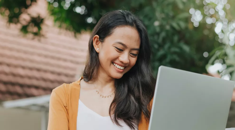 photo of woman smiling while looking at laptop screen