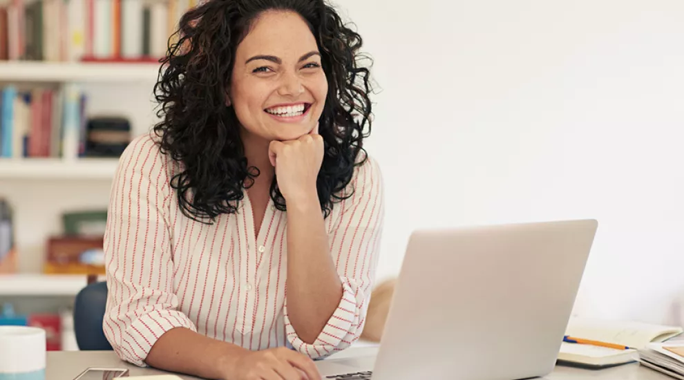 Teacher sitting at laptop smiling