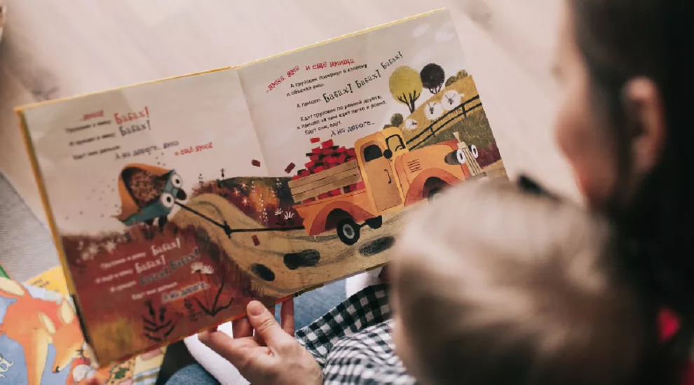 woman reading book to young child