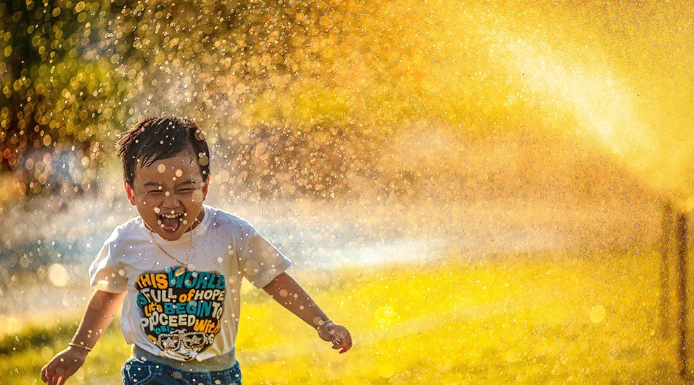 Boy playing in sprinkler