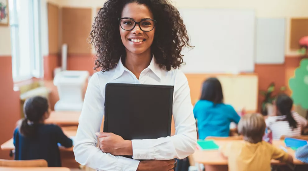 Teacher smiling with class behind her