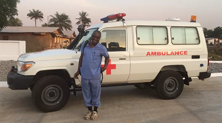 man dressed in scrubs standing in front of ambulance