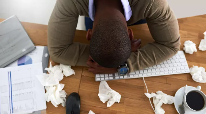 Man laying his head on his desk.