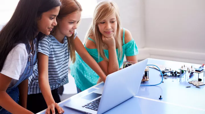 3 young female students looking at a laptop together