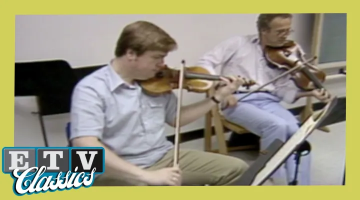 Two violinists practicing during a rehearsal