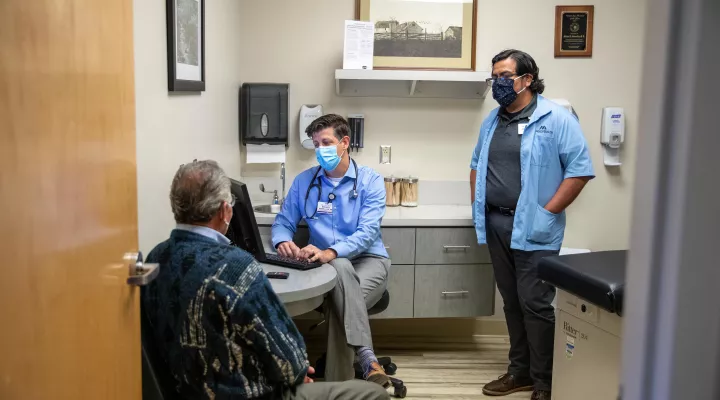 Dr. Michael Seemuller, center, meets with a patient as Jonathan Rios, right, interprets. 