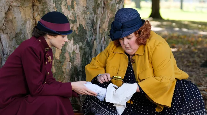 Frankie Drake - Two women examine a cloth with a magnifying glass