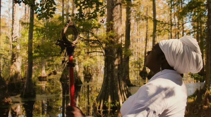 photograph of an African American woman wearing traditional Gullah Folk wardrobe standing near a body of water in the lowcountry of south carolina.
