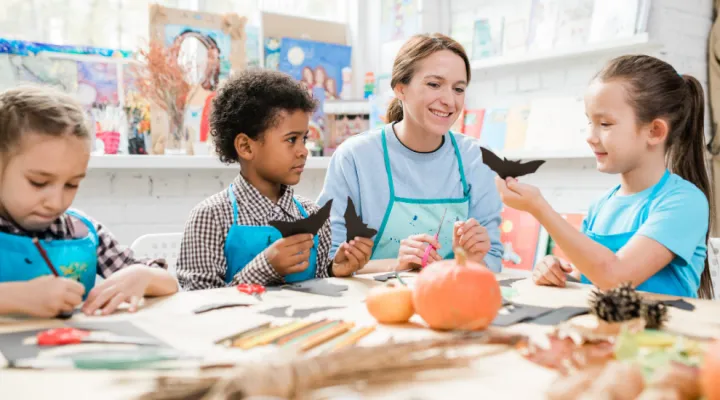 photo of teacher with students cutting bat shapes for Halloween