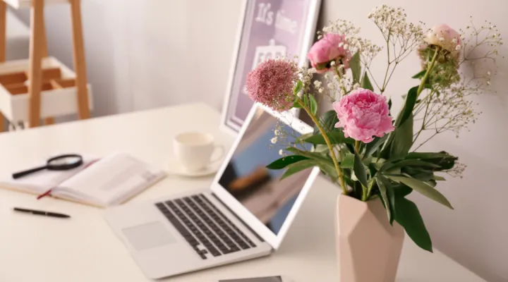 photo of laptop on tabletop with flowers nearby