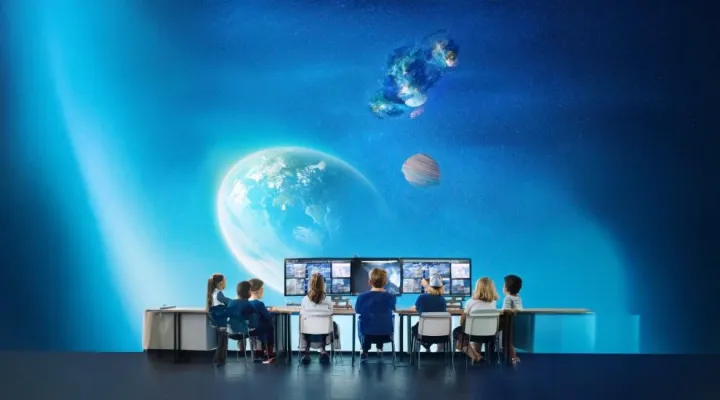 students sitting a desks with video screens. Space in the background