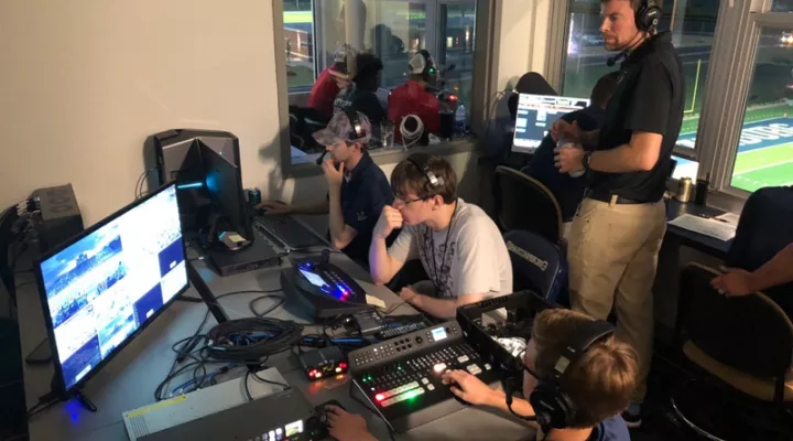 students and supervisor in broadcast control booth