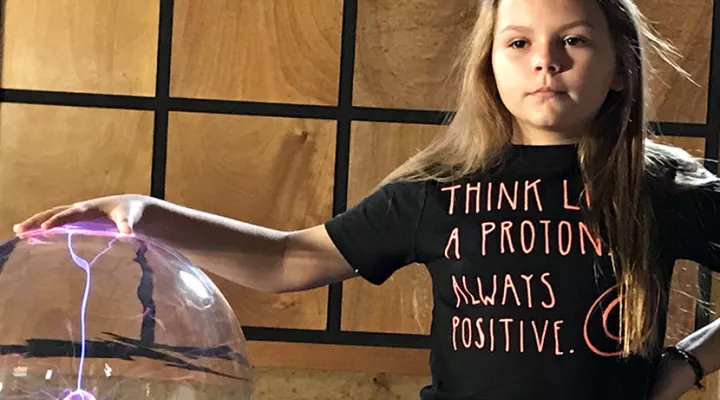 Girl wearing t-shrt that says, "Think like a proton - always positive." 
