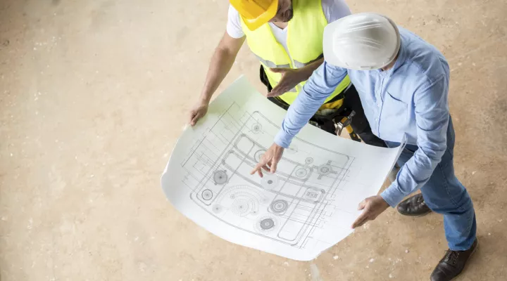 Two construction workers looking at a construction paper