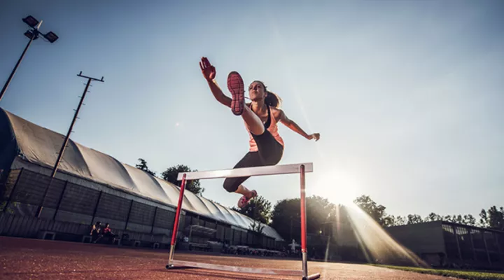 Woman jumping over hurdle