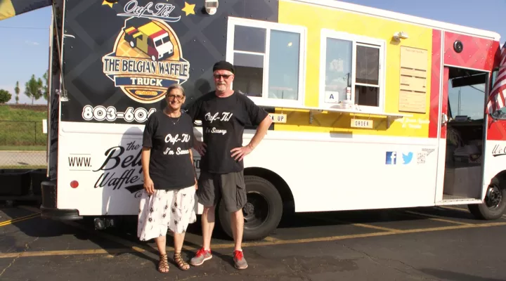 Owners of The Belgian Waffle Truck standing in front of their food truck.