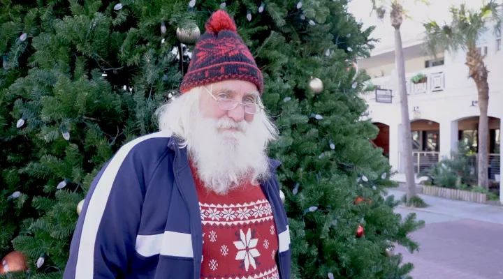 Beach Santa in front of a Christmas tree