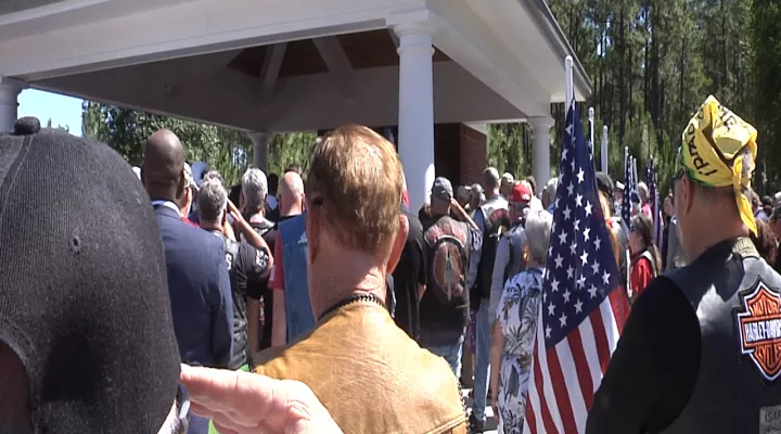 Veterans salute during the playing of taps to honor Petty Officer 3rd Class James Miske