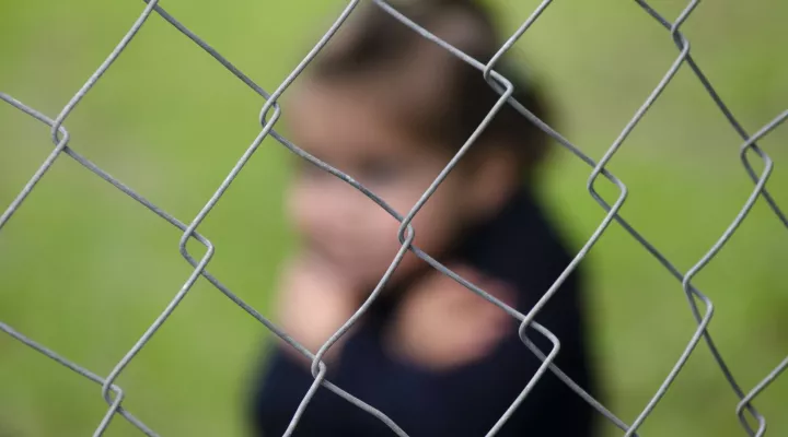 blurred image of child behind a fence