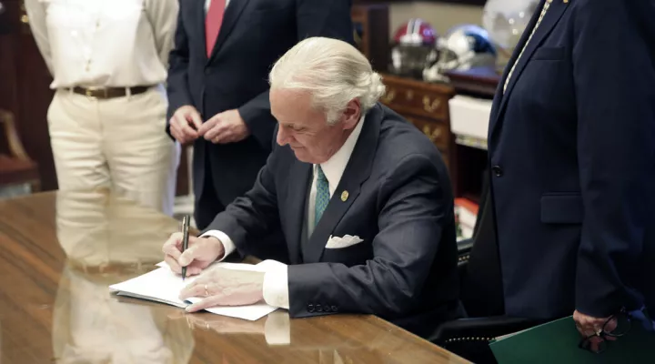 South Carolina Gov. Henry McMaster signs a bill requiring schools to provide in-person classes five days a week starting April 26 and for next school year on Thursday, April 22, 2021, in Columbia, S.C. The bill also requires school districts to pay teachers extra if they have to teach both in person and online. (AP Photo/Jeffrey Collins)