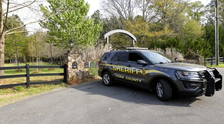 A York County sheriff's deputy is parked outside a residence where multiple people, including a prominent doctor, were fatally shot a day earlier, Thursday, April 8, 2021, in Rock Hill, S.C. A source briefed on the mass killing said the gunman was former NFL player Phillip Adams, who shot himself to death early Thursday. (AP Photo/Nell Redmond)