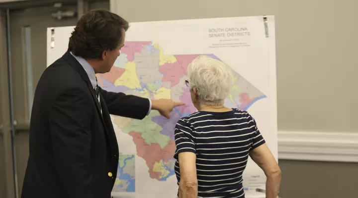 People look over the current South Carolina Senate districts at a public meeting by a Senate subcommittee on redistricting on Wednesday, July 28, 2021, in Sumter, S.C. Senators are holding 10 public hearings across the state. (AP Photo/Jeffrey Collins)
