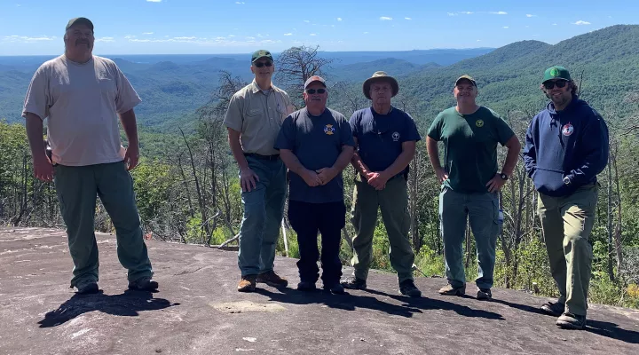  L-R: Ray Cassell, Mike Bozzo, Mike Staton, Ronnie Patterson, Michael Weeks, and Trey Cox were six of the more than 150 firefighters who battled the Pinnacle Mountain fire of 2016. This clearing was one of the safe places they could gather during a monthlong ordeal that ultimately burned 10,000 acres in Pickens County and cost $5 million to fight. 