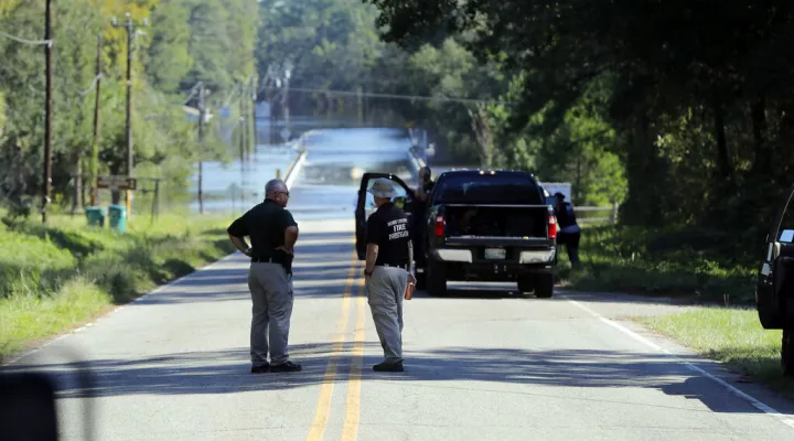 FILE - Responders congregate near where two people drowned the evening before when they were locked in a Horry County Sheriff's department transport van  in Marion County, S.C. A deputy charged in the deaths ignored barricades and drove into rapidly rising floodwaters against advice from his supervisors and officials on the South Carolina highway, a prosecutor said Monday, May, 16, 2022. (AP Photo/Gerald Herbert, File)