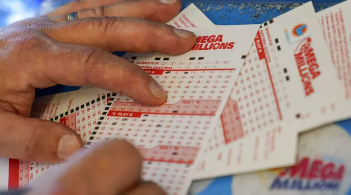 FILE - Gordon Midvale fills out a lottery ticket inside a 7-Eleven store in Oakland, Calif., Tuesday, July 26, 2022.  Across the U.S., state lottery systems use that revenue to boost education, tourism, transportation and much more. Now that the giant Mega Millions lottery jackpot has ballooned to more than $1 billion, state officials are hoping increased national interest in securing the top prize will result in more funding for their own causes. (AP Photo/Godofredo A. Vásquez, File)