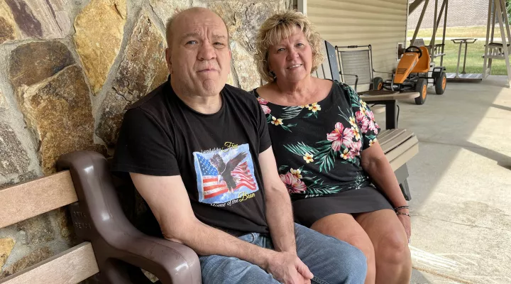 Mike Lee sits with sister Connie Bowen outside the one-story house where he lives on the campus of Iowa’s Glenwood Resource Center, a state-run institution for people with intellectual or developmental disabilities that is set to close in 2024. Lee has lived at the institution for 44 years. 