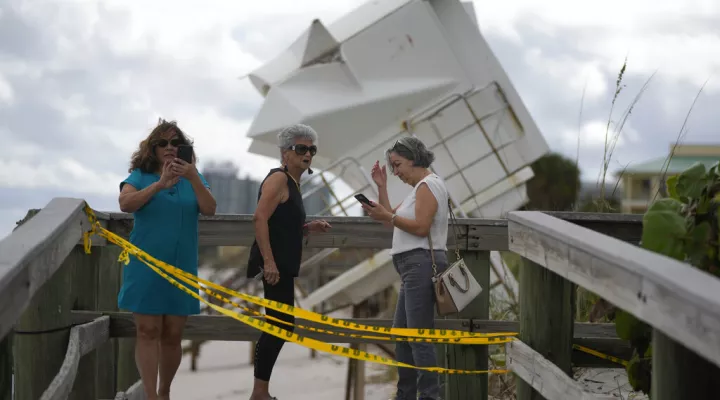 People visit the beach to investigate storm damage, including a lifeguard station that was displaced onto a dune, following the passage of Hurricane Nicole, Thursday, Nov. 10, 2022, in Vero Beach, Fla. (AP Photo/Rebecca Blackwell)